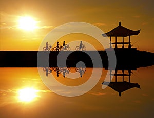 Image Reflection of cyclists riding on a concrete barrier in bali indonesia Sanur beach