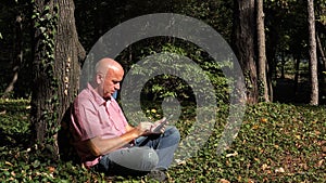 Image with a Relaxed Businessman in Park Texting Using Cellphone Wireless Network