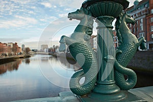 Image of the River Liffey Dublin from Grattan Bridge with Sea Horses bridge ornament statue to the fore .