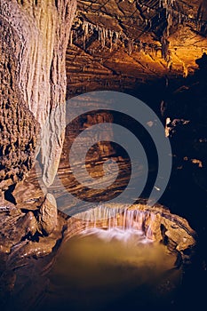 Rock formations in dark cave with underground waterfall