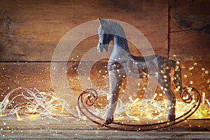 Image of rocking horse and magic christmas lights on wooden table
