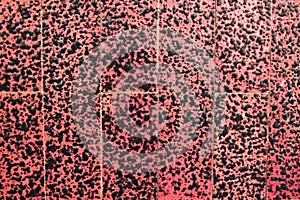Image of a rough surface with a red background and black spots