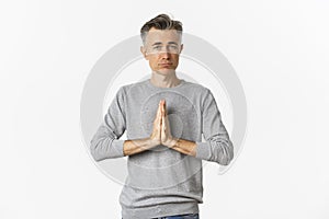 Image of sad middle-aged man begging for help, need something and asking for favour, standing over white background