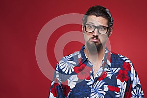 Image of a sad young man in Hawaiian shirt against red background.