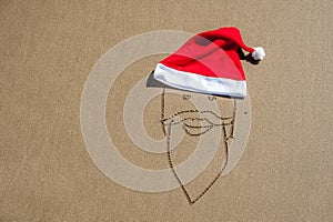 The image of Santa Claus on the sand and a red Santa`s hat