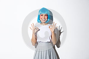 Image of satisfied beautiful asian girl in blue wig showing okay gesture in approval, like something, standing over