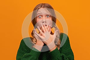 Image of scared blonde teen covering her mouth with hands. Fright, horror concept. Studio shot, yellow background