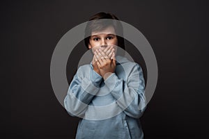 Image of scared boy covering his mouth with hands. Fright, phobia and facial expression concept