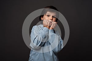 Image of scared boy covering his mouth with hands. Fright, phobia and facial expression concept