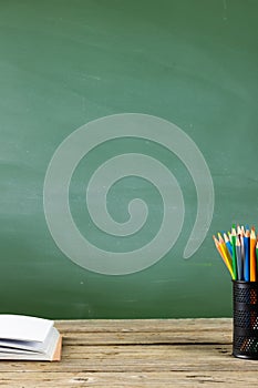 Image of school supplies, apple and notebook over drawings on black board