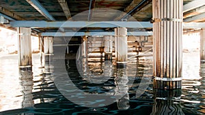Image of sea waves and wooden colums under pier at sea shore