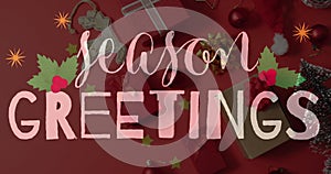 Image of seasons greetings text over christmas decorations