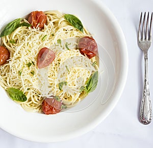 Plate of spaghetti with cherry tomatoes, basil and grated cheese photo