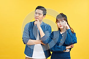 Image of serious man and woman in casual wear touching chins and looking aside isolated over colorful background