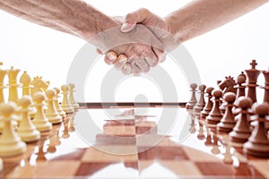 Image of shaking hands over chess on a white background