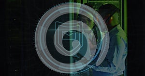 Image of shield icon over african american male and female engineer using laptop at server room