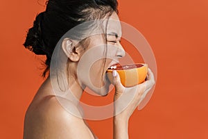 Image of shirtless asian beautiful girl eating grapefruit