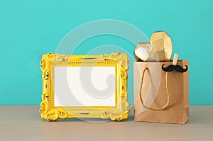 Image of shopping bag, present for dad next to empty photo frame for photography montage. Father`s day concept.