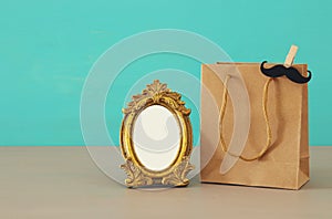 Image of shopping bag, present for dad next to empty photo frame for photography montage. Father`s day concept.