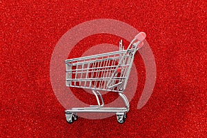 Image of shopping cart over red glitter background