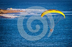 Image shot from slightly above a Paraglider at an altitude of  about 500 feet headed toward people on beach and lifeguard tower