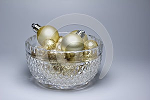 Macro abstract art texture of sparkling gold glitter Christmas ornaments and balls, in a crystal bowl on a white background