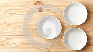 Three empty white plates on a wooden table.