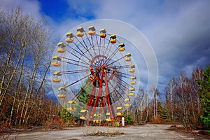 The image shows an unused, rusty Ferris wheel with yellow cabins