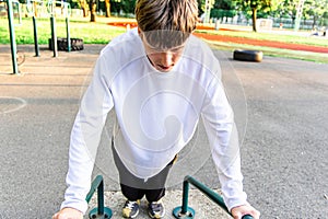 Young Man Doing Dips On Outdoor Exercise Equipment