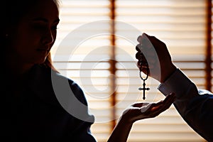 Image is Silhouette. Asian man is giving a cross to a Christian woman with a smiling face. To pray to Jesus Confession to God.