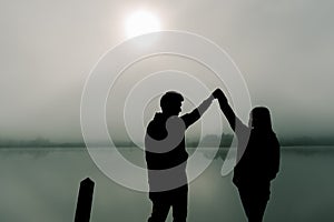 Image of Siluette, a lovely Asian couple, bright and bright, standing in the tourist area. Along the road in the fog The back is a