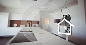 Image of silver house keys and house shaped key fob hanging over an out of focus kitchen 4k