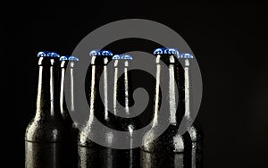 Image of six beer bottles with blue crown caps, with copy space on black background