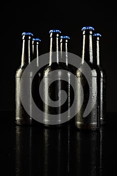 Image of six beer bottles with blue crown caps, with copy space on black background