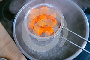 The image of a small amount of chopped carrots over a boiling pan