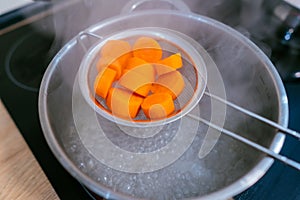 The image of a small amount of chopped carrots over a boiling pan