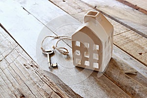 Image of small miniature house and old key over rustic wooden table.