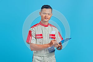 Image of smiling asian handsome man wearing mechanic uniform taking notes on clipboard