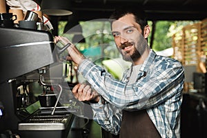 Image of smiling barista man making coffee while working in cafe or coffeehouse outdoor photo