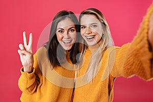 Image of smiling beautiful women showing peace sign while taking selfie