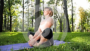 Image of smiling middle aged woman in fitness clothes doing stretching and yoga exercises. WOman meditating and doings