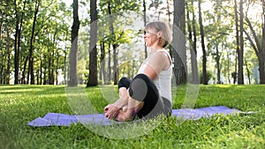 Image of smiling middle aged woman in fitness clothes doing stretching and yoga exercises. WOman meditating and doings