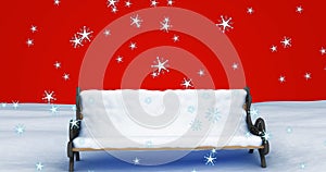 Image of snow falling over snow covered bench on red background