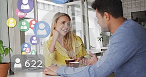 Image of social media icons floating over happy caucasian couple talking and drinking coffee