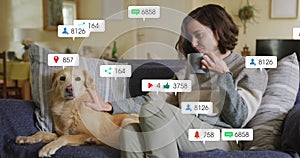 Image of social media icons and numbers over caucasian woman with pet dog at home