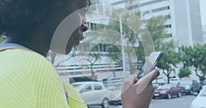 Image of social media notifications over happy african american woman using smartphone in street