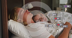 Image of social media notifications over happy couple asleep in bed embracing