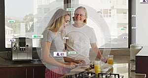 Image of social media notifications over smiling couple preparing breakfast in sunny kitchen