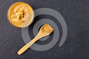 Image of spoon and bowl with peanut butter on dark grey surface