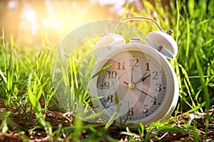 Image of spring Time Change. Summer back concept. Vintage alarm Clock outdoors.